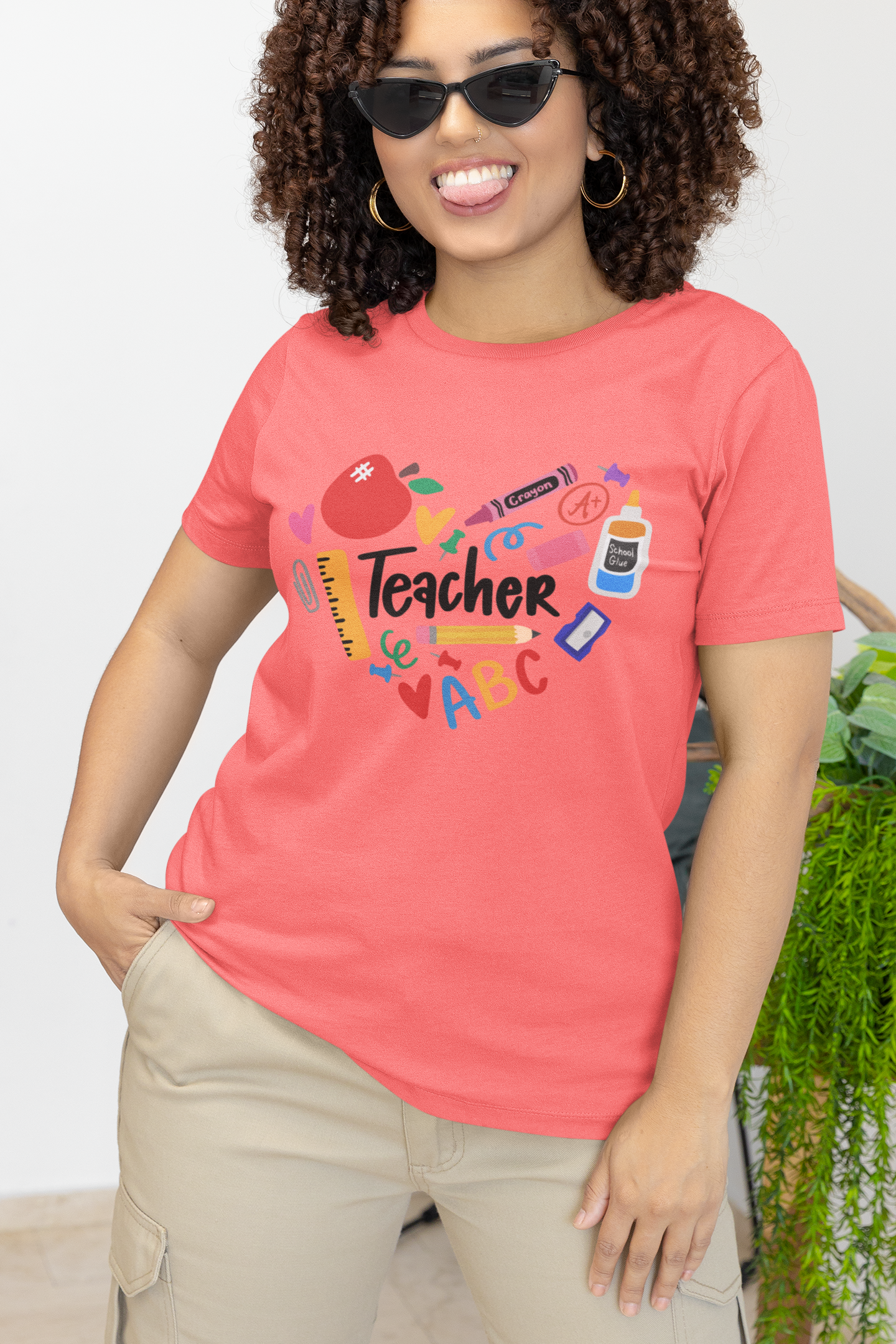 Pink T-shirt with 'Teacher' graphic, featuring colorful school supplies such as crayons, ruler, apple, and more