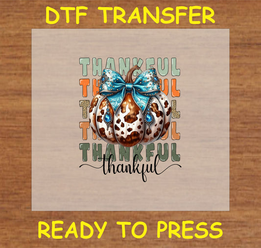 "Thankful DTF Transfer with cow print pumpkin, blue bow with gem accents, and 'Thankful' text for fall decor"