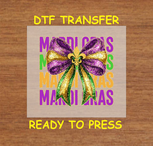 DTF transfer featuring a glittery purple, green, and gold bow with a fleur-de-lis and "Mardi Gras" text in bold, festive colors.