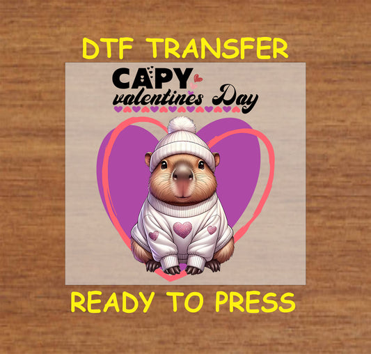 "DTF transfer featuring a capybara in a sweater with hearts, surrounded by pink and purple heart designs for Valentine's Day."