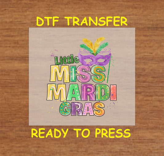 Little Miss Mardi Gras DTF transfer with colorful text and a festive masquerade mask with feathers.