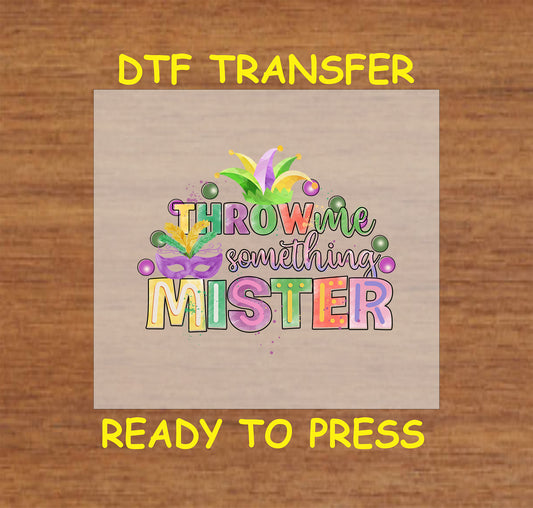 Throw Me Something Mister DTF transfer with colorful text, a masquerade mask, beads, and festive feathers.