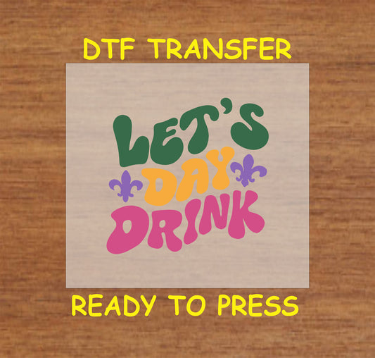 DTF transfer with "Let’s Day Drink" text in bold colors with fleur-de-lis accents.