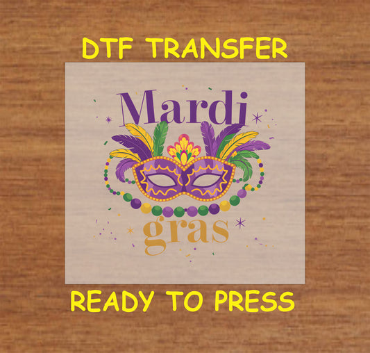 DTF transfer with a Mardi Gras mask, feathers, and festive beads in purple, green, and gold.