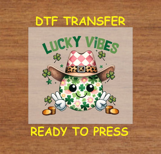 St. Patrick’s Day DTF transfer with a smiley face, shamrocks, a cowboy hat, and gold coins.