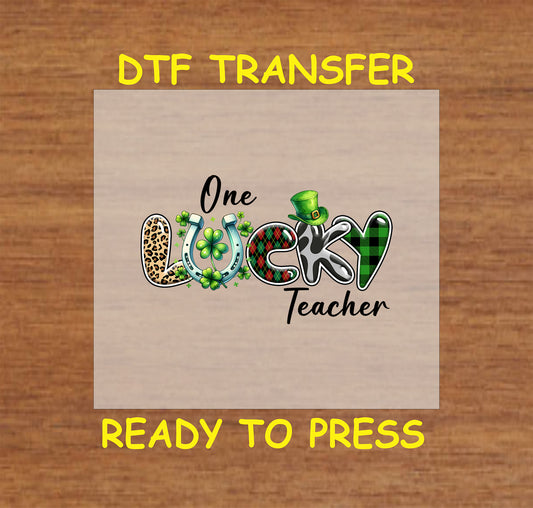 St. Patrick’s Day DTF transfer with "One Lucky Teacher" text, shamrocks, plaid, leopard print, and a lucky horseshoe.