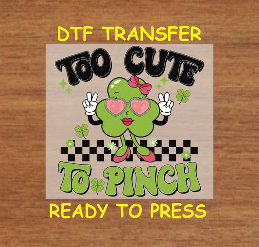 St. Patrick’s Day DTF transfer featuring a shamrock character with heart-shaped glasses, a bow, and heels, with “Too Cute to Pinch” text.