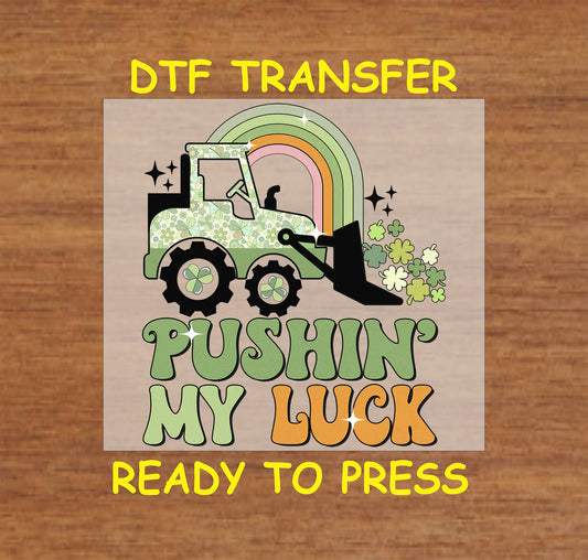 St. Patrick’s Day DTF transfer featuring a construction vehicle pushing shamrocks under a rainbow with “Pushin’ My Luck” text.