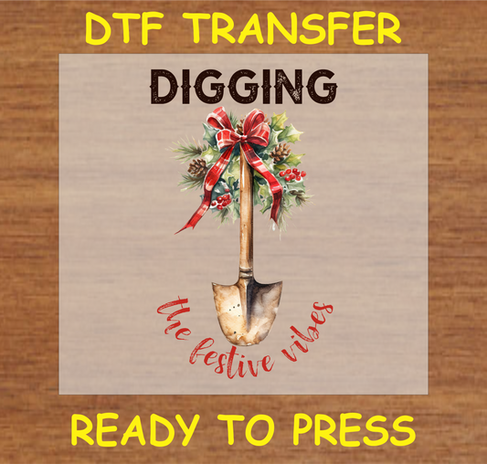 "Digging the Festive Vibes DTF Transfer featuring a rustic shovel adorned with holiday greenery and ribbon"